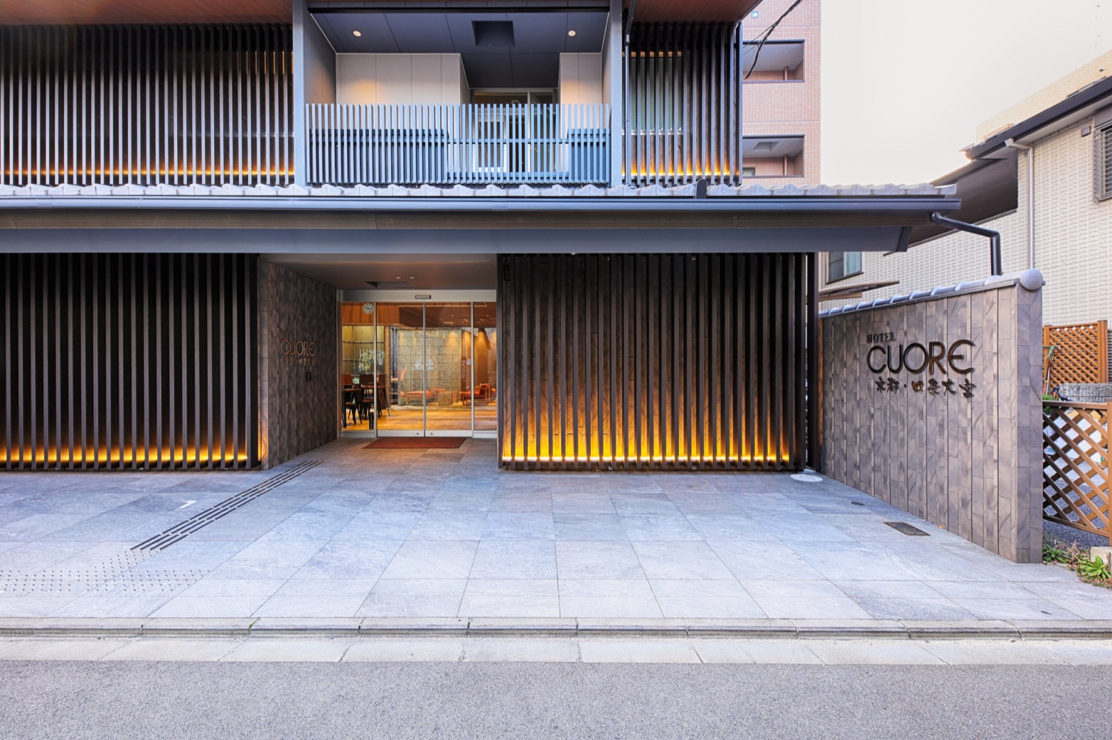 ホテル正面の外観。瓦庇と黒い木格子、右手の石壁にHOTEL CUORE 京都・四条大宮のサイン