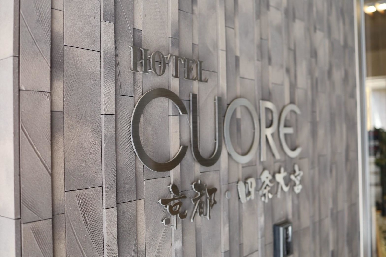 石張りの壁に取り付けられたHOTEL CUORE 京都・四条大宮の金属製サイン